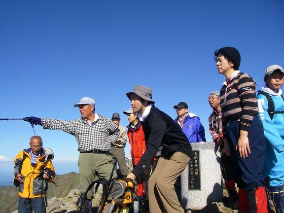 朝日軍道の説明を聞く登山参加者たちの写真