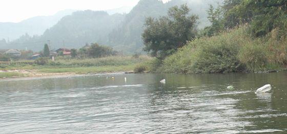 川の流れに沿って仕掛けた網をめざして舟を進めている写真