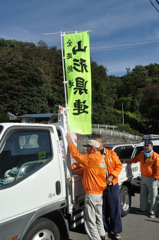 作業に向かう車にのぼり旗を掲げている写真