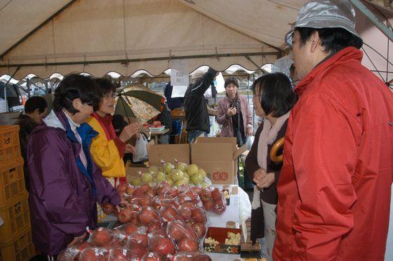 外のテントで農家自らがりんごを販売している様子の写真