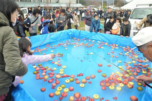 りんご釣りゲームを楽しむ親子の写真