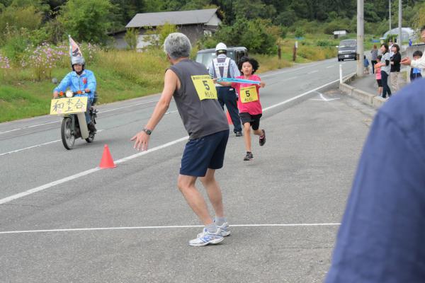 朝日町ワイン城前の中継地でタスキを渡そうとする選手の写真