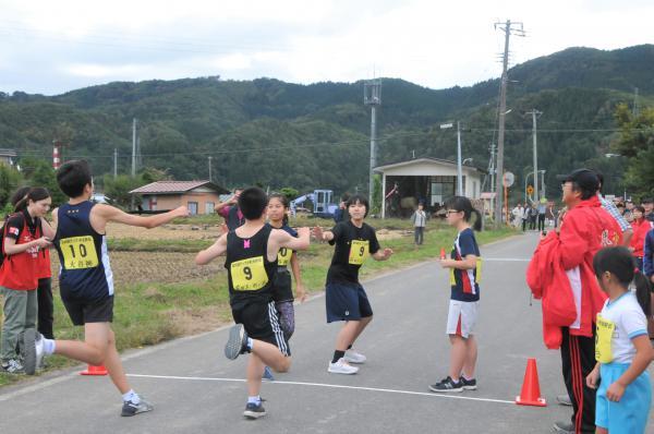 「前田沢」と「大谷風」の選手が10区の選手へタスキリレーしている写真