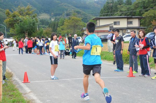 道で選手が仲間へタスキを託す写真