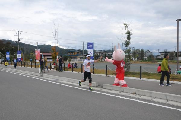 町PRキャラクター桃色ウサヒとハイタッチする選手の写真