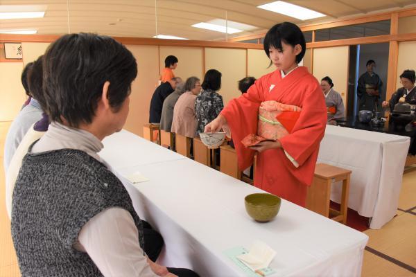 和服の女の子がお茶の給仕をお手伝いする様子の写真