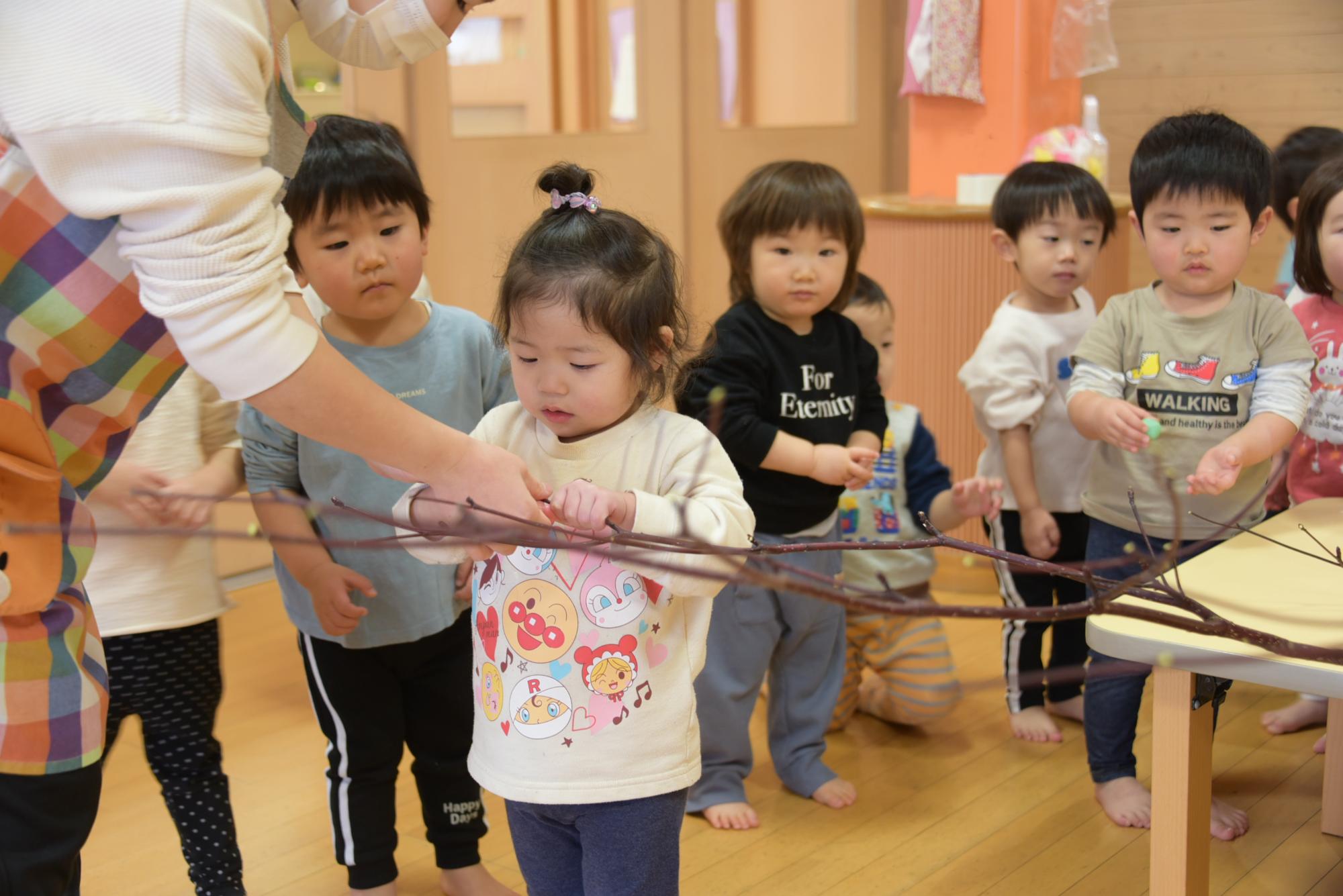 枝に団子を刺す子どもたち