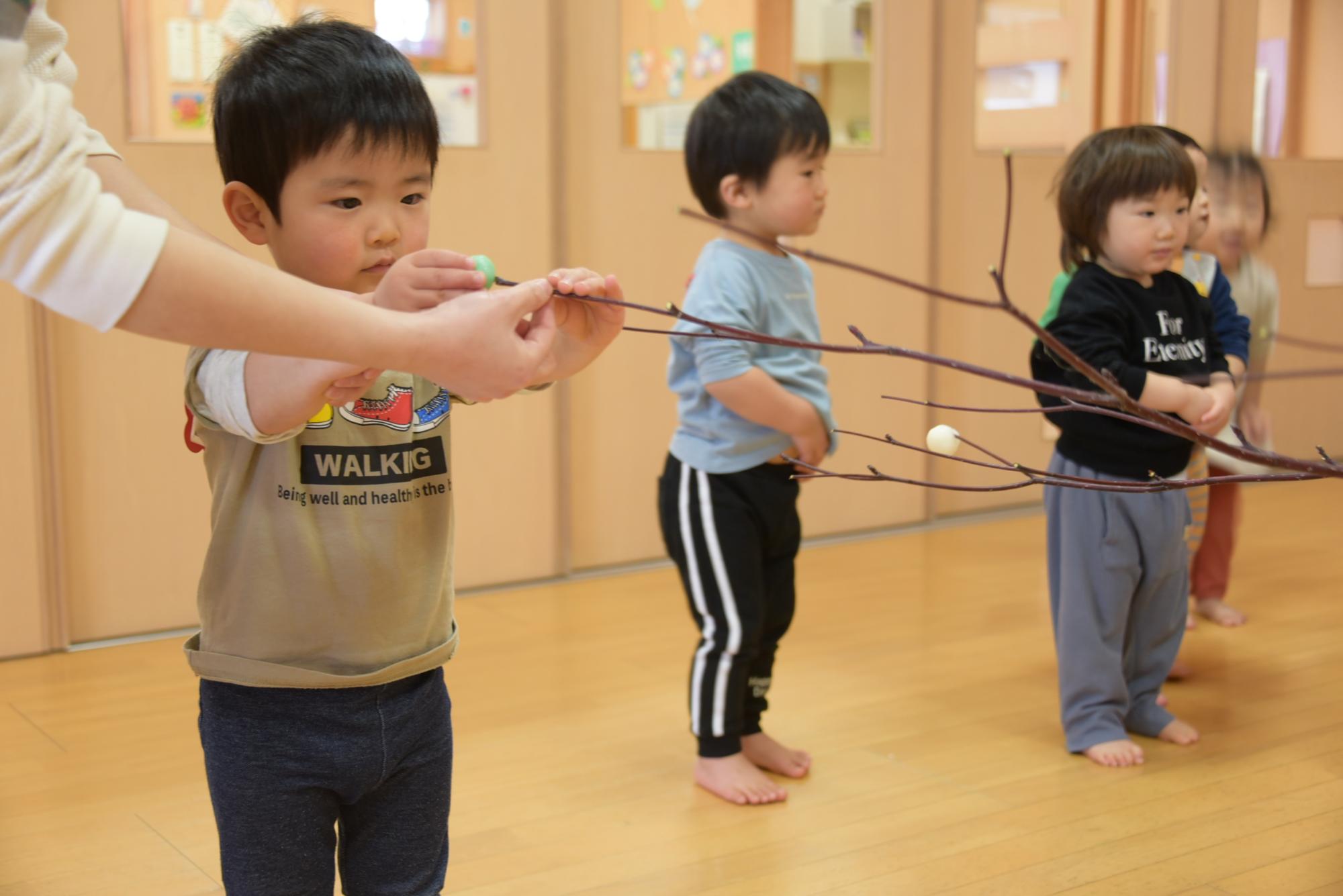 枝に団子を刺す子どもたち