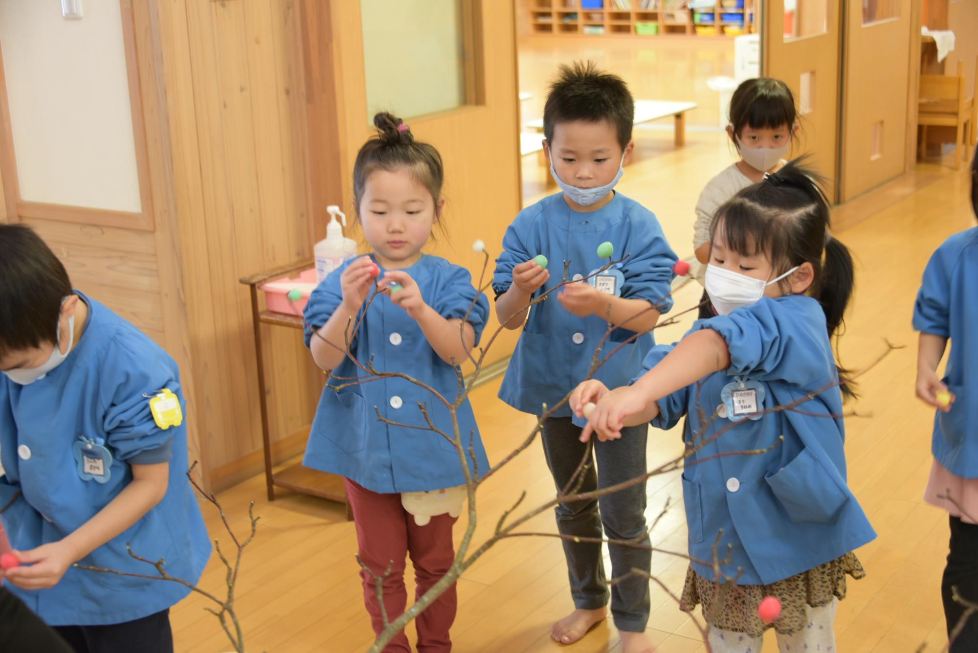 枝に団子を刺す子どもたち