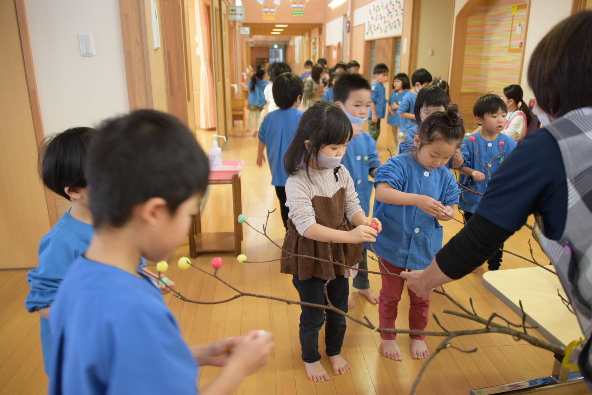 枝に団子を刺す子どもたち