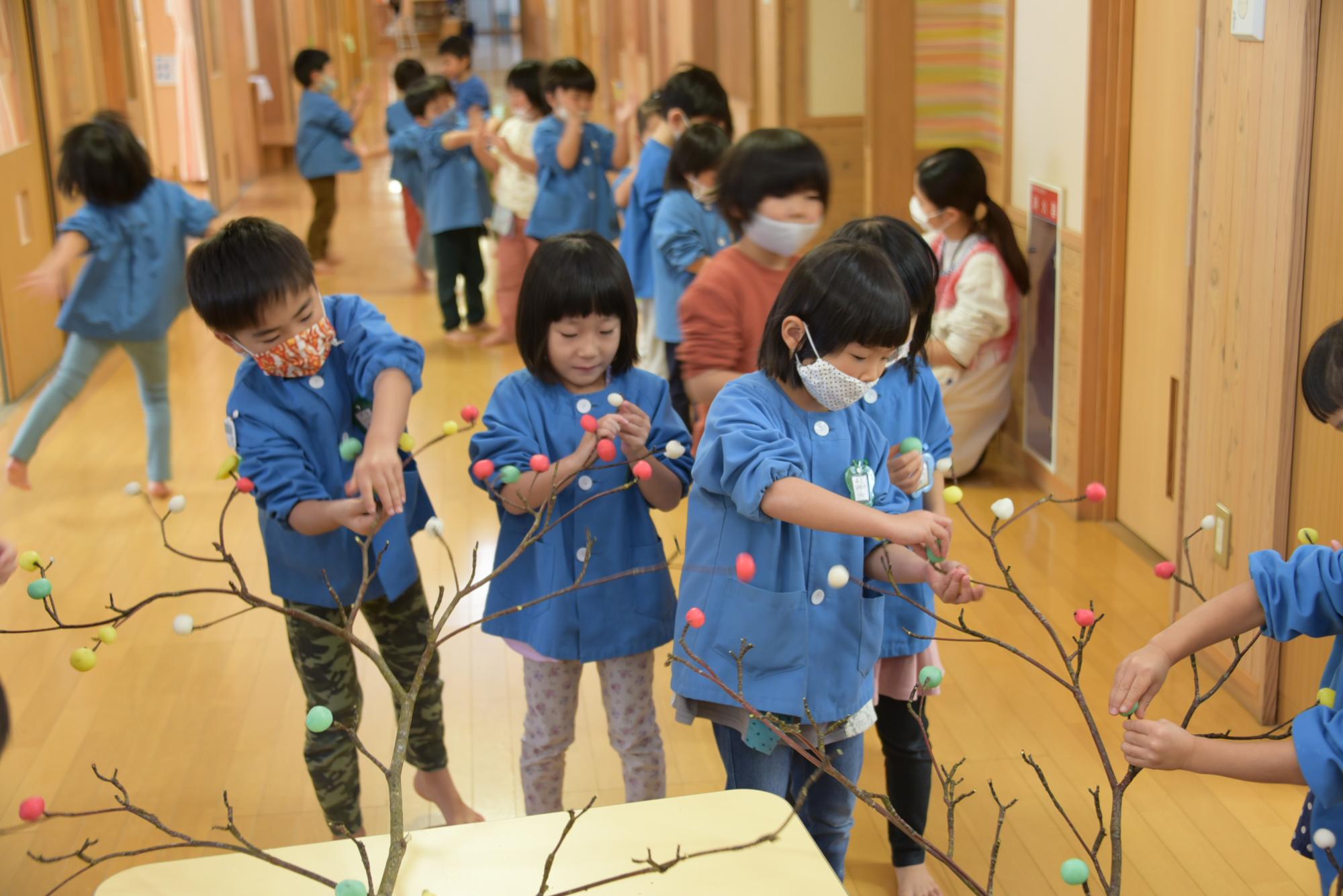 枝に団子を刺す子どもたち