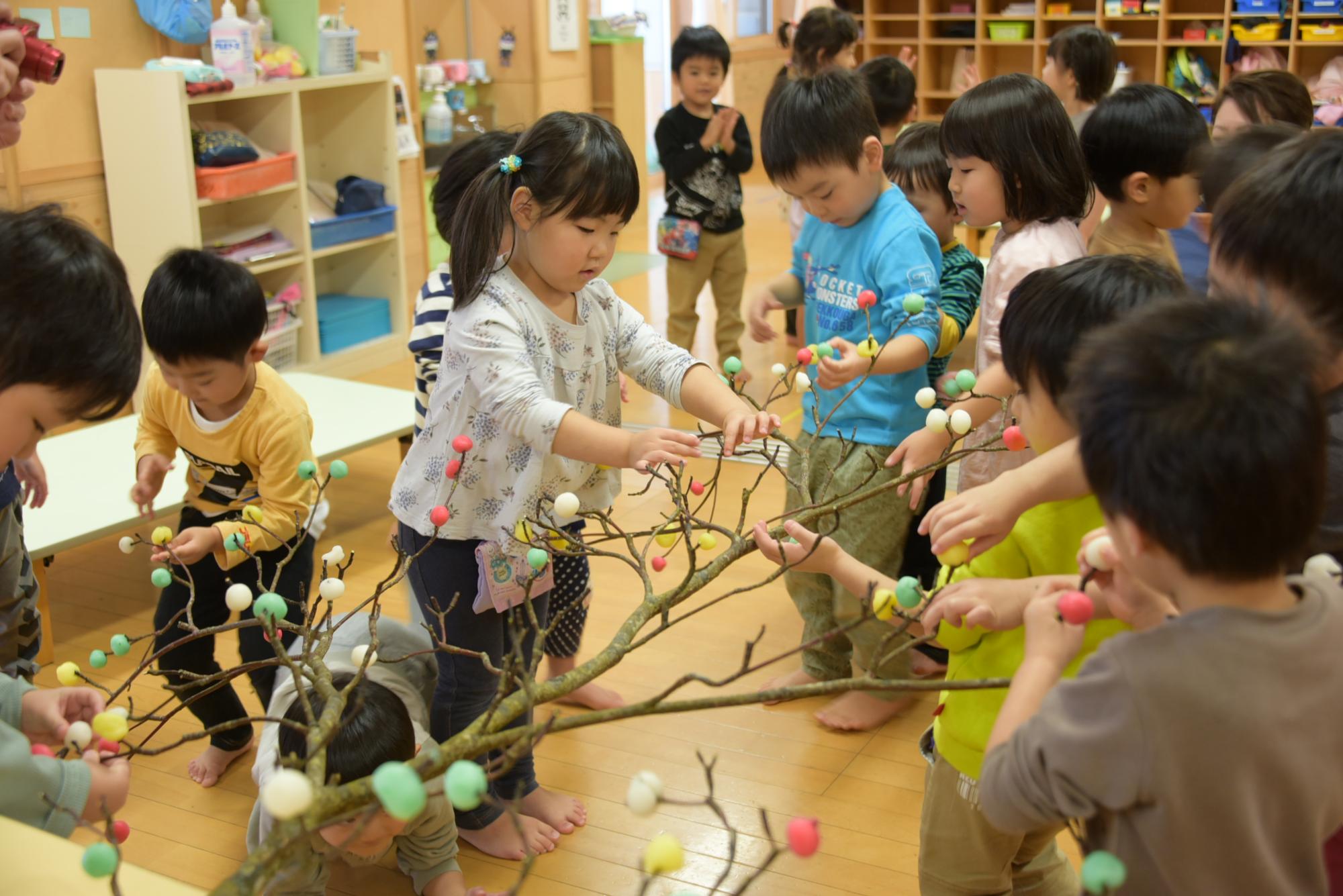 枝に団子を刺す子どもたち