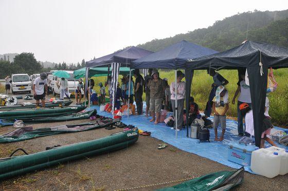 合同カヌー遊びの準備の途中で雨に見舞われ、テントに一時避難している様子の写真