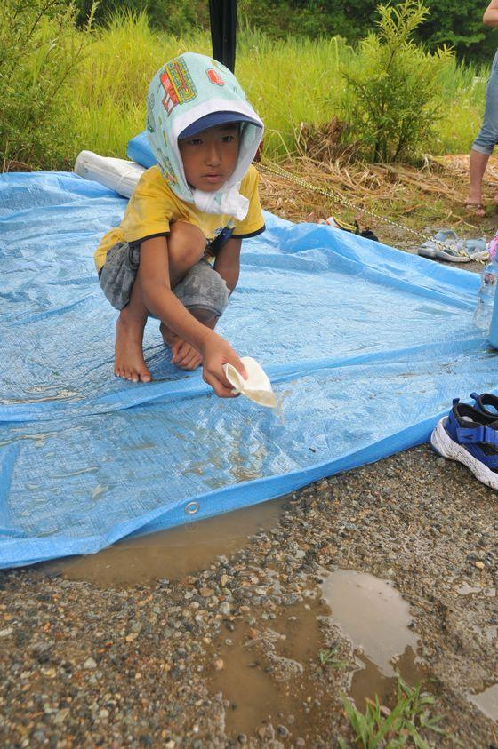 床上浸水した雨水をかき出している子どもの写真