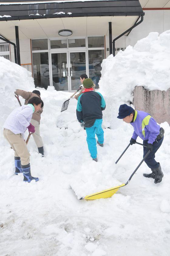 雪に埋もれていた入口階段の雪かきをする様子の写真