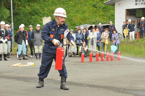 消火器を使った初期消火訓練で消防団幹部がはじめに手本を示している様子の写真