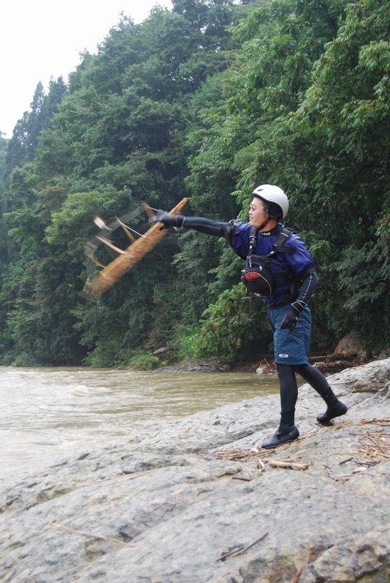 手作りのオブジェを最上川に投げ入れる遠藤牧人さんの写真