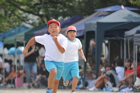 低学年による70メートル走で競り合う2人の男児生徒の写真