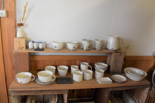 白いシンプルなデザインの陶器が並ぶ棚の写真