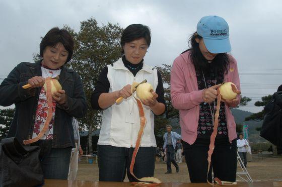 和合りんごまつりでりんごの皮を剥く女性たちの写真