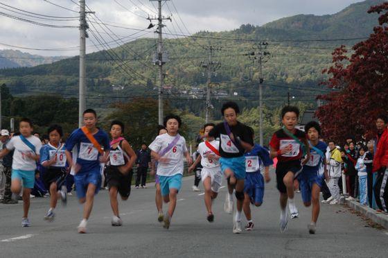 道路を横に並んで走っている小学生の写真