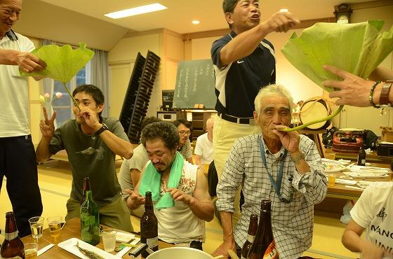 ハスの葉を使って酒を飲んでいる区長の田川順一さんの写真