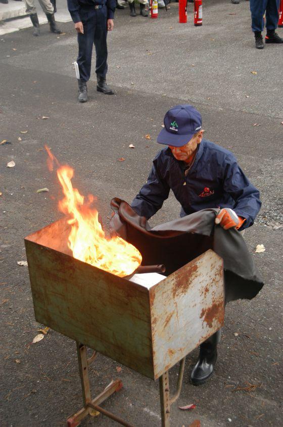 防火シートを使った天ぷら鍋の消火訓練の様子の写真