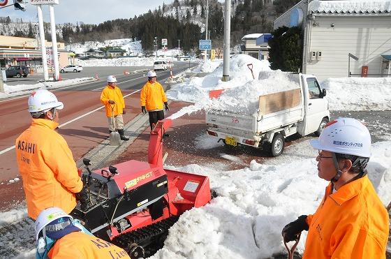 除雪機と軽トラックで雪を処理している写真