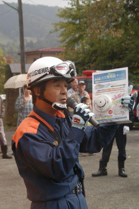 家庭用火災報知機の設置義務を説明する消防隊員の写真