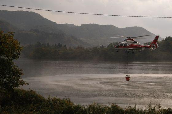 防災ヘリが上郷ダムで取水をしている様子の写真
