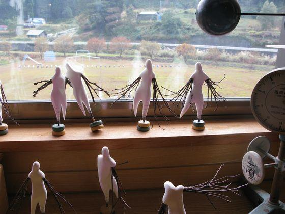 旧立木小学校の教室に展示している両腕から複数の枝が生えたような小さな白い人形たちの写真