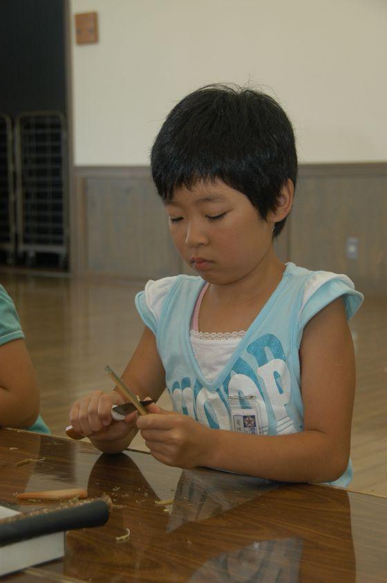 竹を削って箸を作っている子どもの写真