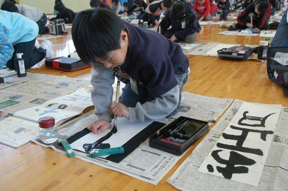 宮宿小書き初め大会で、「お正月」と書こうとしている左利きの3年生児童の写真