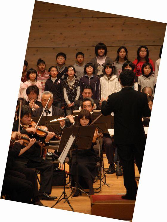 「第3部オーケストラと歌おう」で歌う小学生たちと指揮者の写真