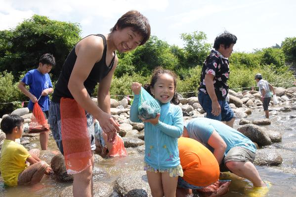 網に入った魚を掲げる女の子とお父さんの画像