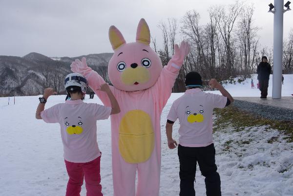 ウサヒをはさんで雪の中半袖のウサヒシャツを着て記念撮影の写真