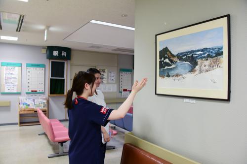 受付・会計待合ホールに飾られた作品を前に話をしている病院スタッフの写真